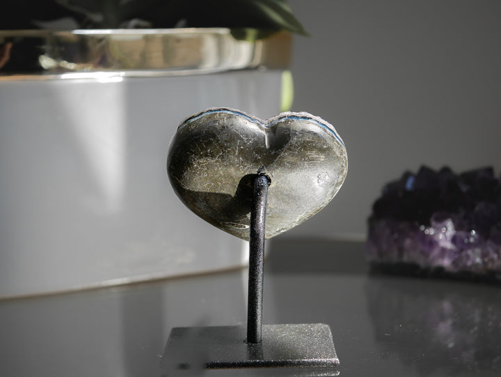 Picture of the back natural Heart-shaped rainbow amethyst crystal on a stand